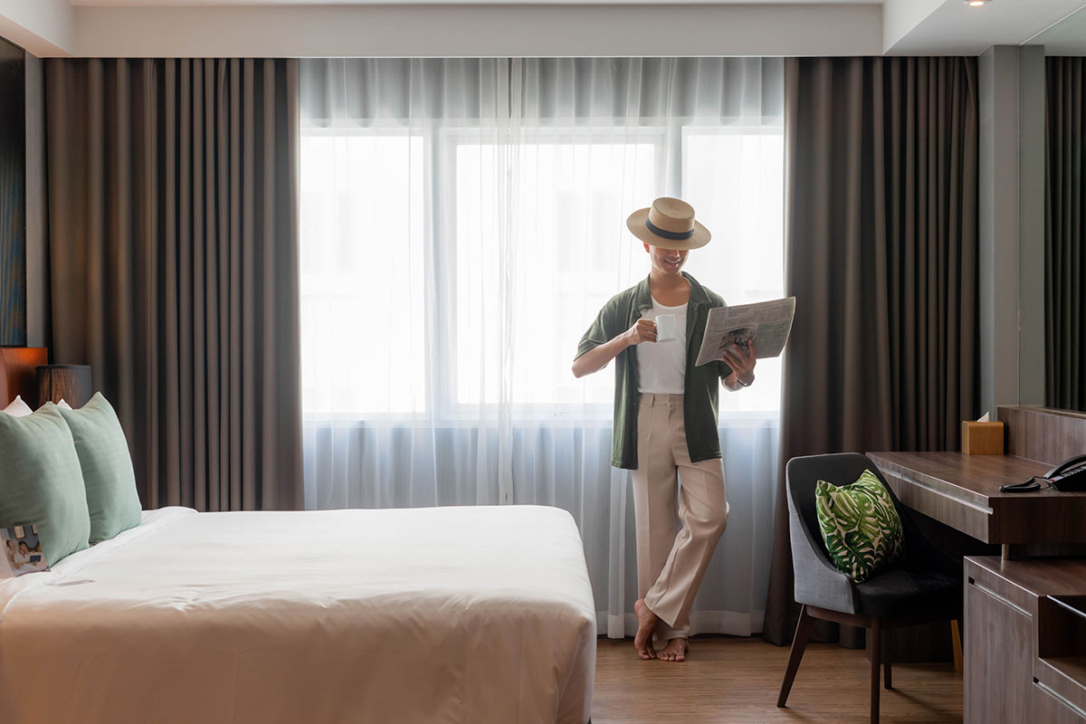 Spacious Deluxe Studio Room with a king-size bed, modern decor, seating area, and warm lighting for a relaxing stay.