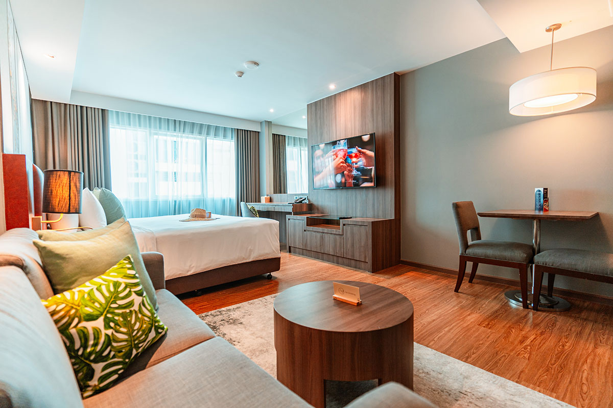 Spacious Deluxe Studio Room with a king-size bed, modern decor, seating area, and warm lighting for a relaxing stay.
