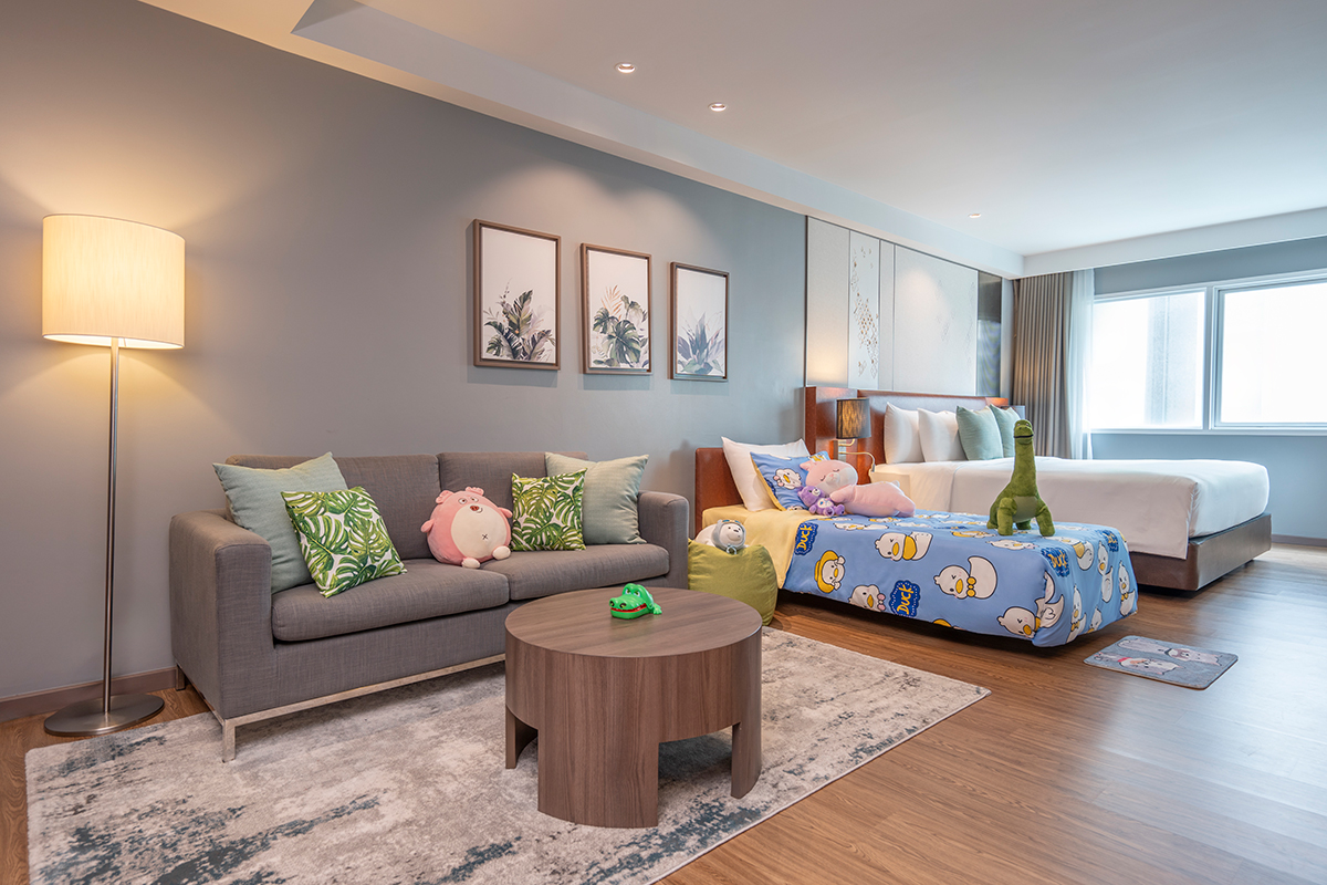 Spacious Deluxe Studio Family Triple King Bed with a king-size bed, modern decor, seating area, and warm lighting for a relaxing stay.