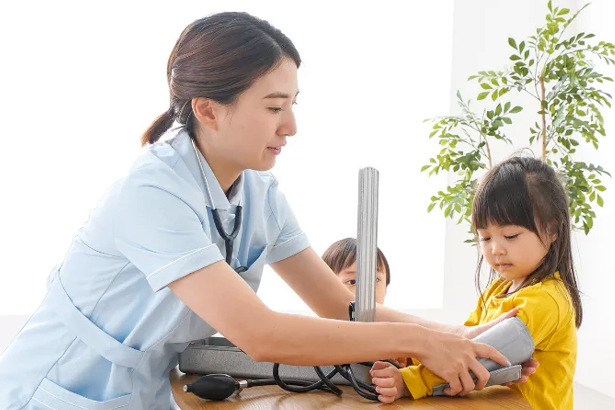 Smiling nanny playing with young children in a hotel room, providing safe and caring childcare service.